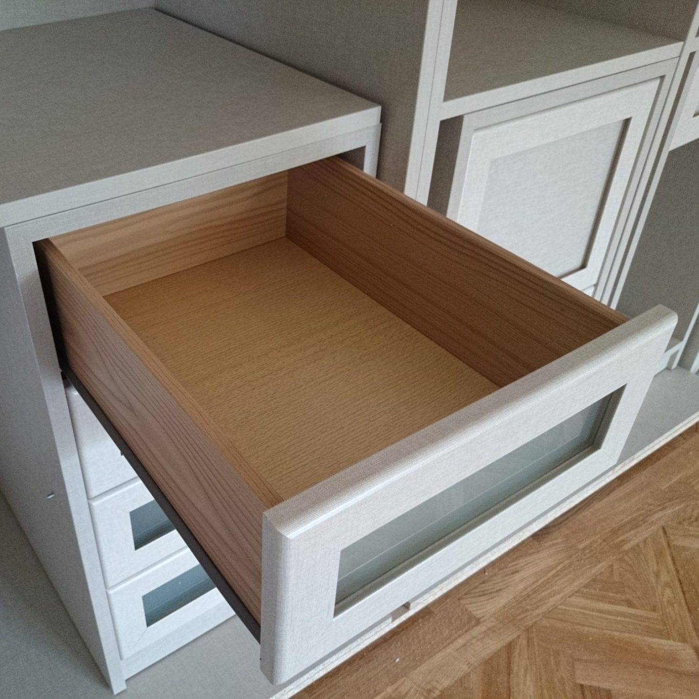 Cajón abierto de mueble, con interior de madera clara y exterior de acabado blanco.